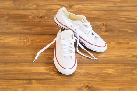 beautiful white sneakers are standing on dark wooden floorの写真素材