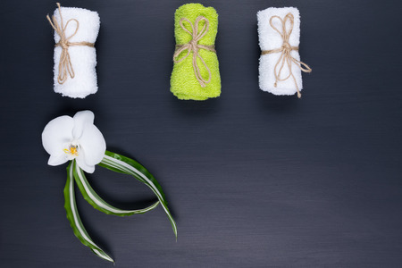 Three different towels are lying on a black background and a white orchidの写真素材