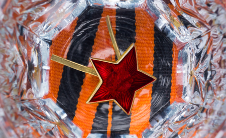 Red star in a faceted glass of vodka for the day of victoryの写真素材