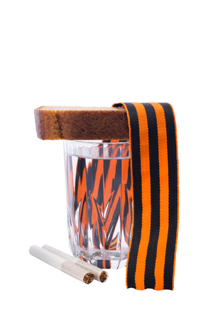 St. George ribbon on a glass of vodka with bread next to two cigarettes, isolated on a white backgroundの写真素材