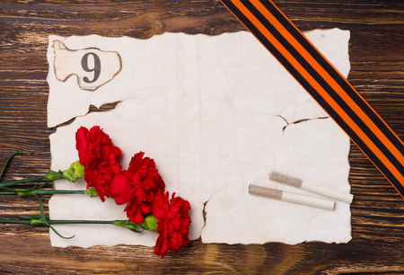 Vintage background for a victory day postcard, with a red carnation, two cigarettes and a 9 digitの写真素材