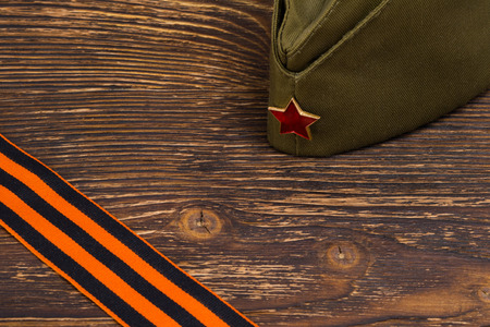 Military cap on a wooden table and place for inscription and St. George's ribbonの写真素材
