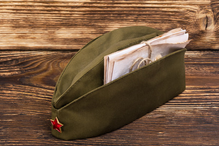 Old letters lie in a military cap with a red star, on an old tableの写真素材