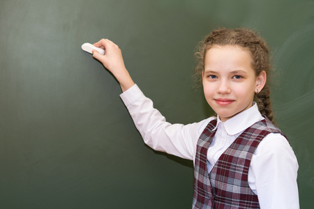 girl in a school uniform is standing in front of a green boardの写真素材