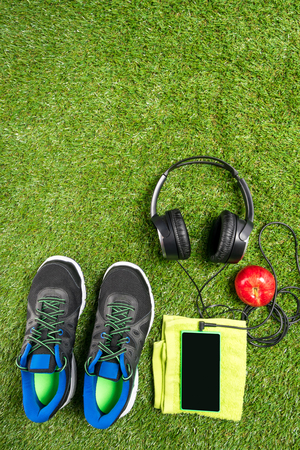 sneakers with music and a red Apple on a background of green grassの写真素材