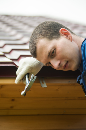man holding a hammer in the background of the roofの写真素材
