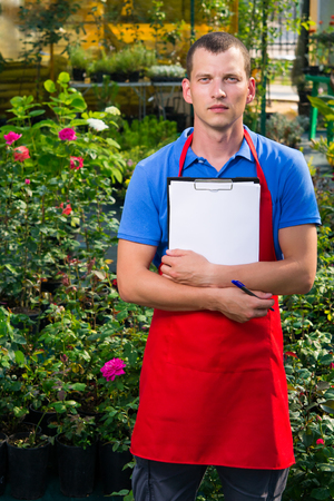 Caucasian man is taking notes in a flower greenhouseの写真素材