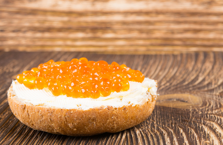 Round sandwich with butter and red caviar on a wooden backgroundの写真素材