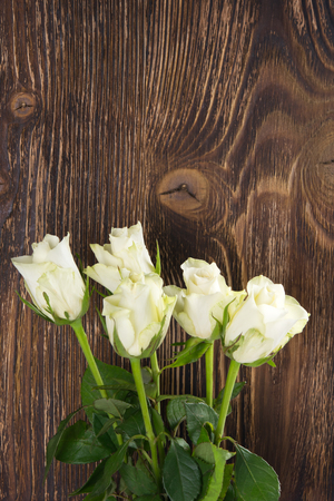 A bouquet of white roses on a background of a dark wooden structureの写真素材