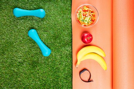 Set of sports nutrition and dumbbells on green fieldの写真素材