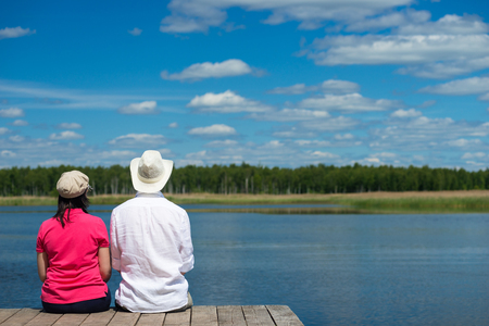 Man and woman are sitting on the shoreの写真素材