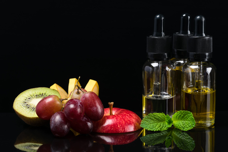 Fruit flavors liquids for electronic cigarettes, concept on a black backgroundの写真素材