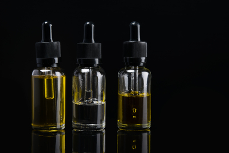 three liquid bottles for e cigarette on black backgroundの写真素材