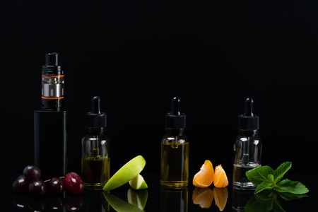 Fruit flavors in bottles for an electronic cigarette on a black backgroundの写真素材