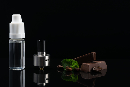 Aroma of chocolate and mint for refueling an electronic cigarette, concept with reflection on a black backgroundの写真素材