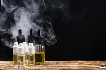 Bottles with fragrant liquids for an electronic cigarette on a black background with the rightの写真素材