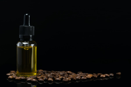bottle with the aroma of coffee stands in beans on a black backgroundの写真素材