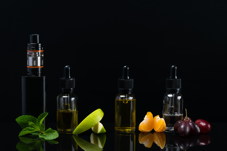 Black background with a set of fruit flavors with reflection on the surface for an electronic cigaretteの写真素材