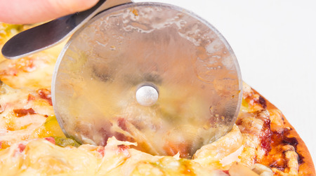 Pizza is cut into pieces with a knife roundの写真素材
