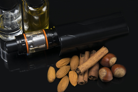 Electronic cigarette with nuts and cinnamon on a black backgroundの写真素材
