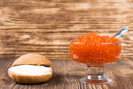 Old wooden background with a plate of red caviar, place for inscriptionの写真素材