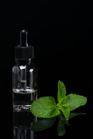 Liquid with a scent of green mint in a bottle on a black backgroundの写真素材