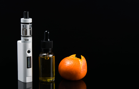 Electronic cigarette and liquid with orange taste, on a black backgroundの写真素材