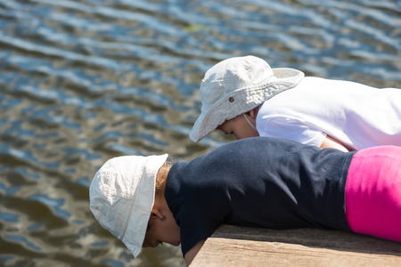 Brother and sister playing with water on the pierの写真素材