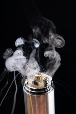 Checking the operation of an electronic cigarette with smoke on a black backgroundの写真素材
