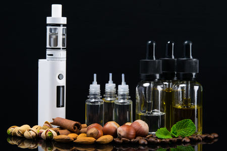 Liquid for an electronic cigarette in bubbles surrounded by nuts, cinnamon and fresh mintの写真素材