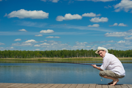 man in a hat and a white shirt, is fishing on the lakeの写真素材