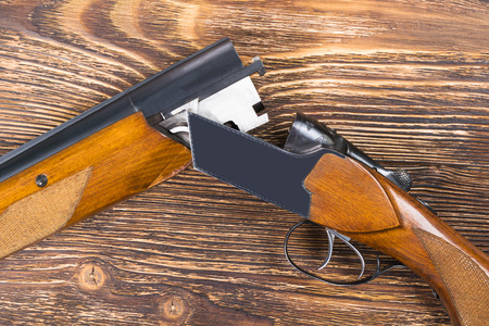 An open rifle with cartridges rests on a wooden table
