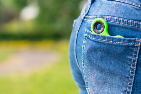 Green spinner toy for nerve lies in a pocket on a background of green grassの写真素材