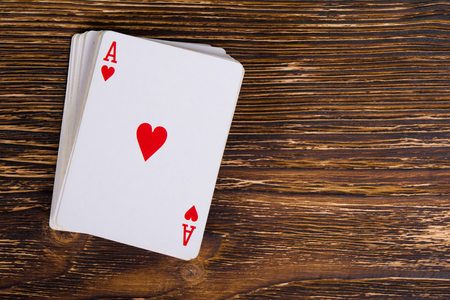 A deck of cards with an ace on a dark wooden table