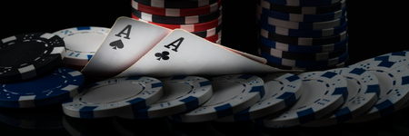 Two black aces on poker cards glow in a dark casino