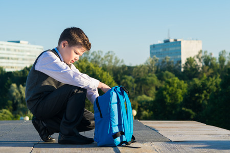 Boy in school clothes collects a bag for schoolの写真素材