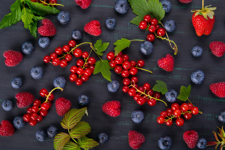 Black background with red currant berries on the surface mixed with blueberriesの写真素材