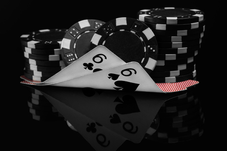two small cards in poker under the poker chips reflected on black backgroundの写真素材