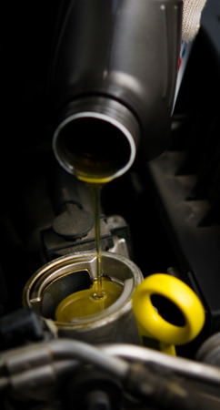 new oil flows from the bottle into the engine of the carの写真素材