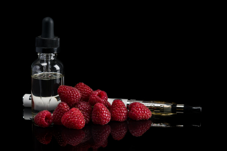 electronic cigarette with raspberries and bottle of berry taste, concepts of wapes on a black backgroundの写真素材