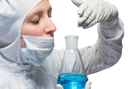 Young female scientist in uniform smelling liquid in a flask, isolated on white