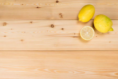 two yellow lemons and a half on wooden boards, a place for writingの写真素材