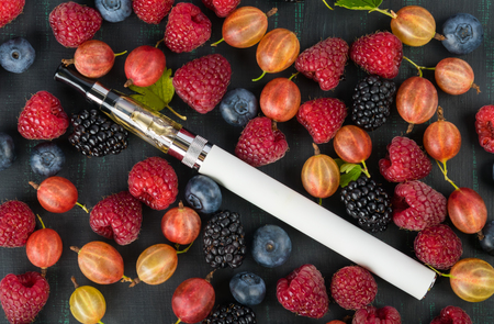 Electronic cigarette in the center of a background of small berriesの写真素材