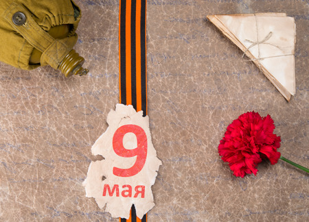 an inscription on May 9 on the St. George ribbon, with a carnation, old letters and a flask, against...