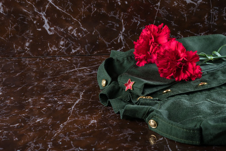 Red flowers and military uniform on dark marbleの写真素材