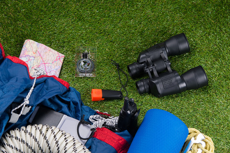 on the green lawn, a set of objects for tourism, binoculars, flashlight, compass, tent, camping Mat.の写真素材