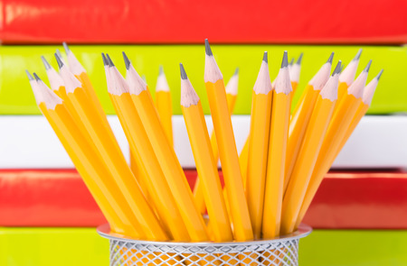 pencils in a metal Cup in the background. colorful books.の写真素材