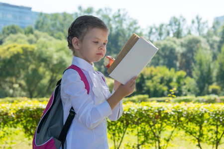 girl in the open air, reading a book and eating a red appleの写真素材