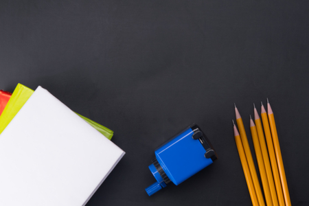 on a black background, for an inscription from above, from below lie pencils, a sharpener and booksの写真素材