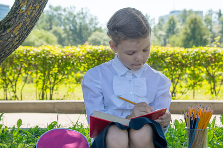 the girl is engaged, outdoors, and makes notes in the book
